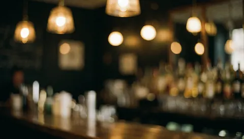 Arrière-plan de bar avec lumières chaudes et effet bokeh, idéal pour textes ou contenu promotionnel, ambiance cosy et sophistiquée.