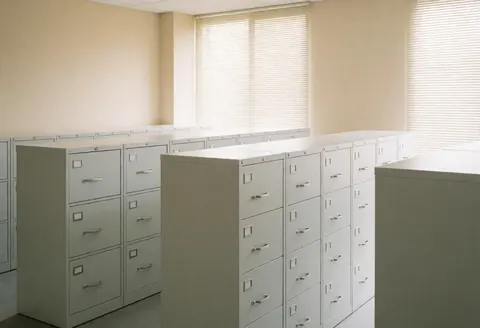 Bureau des ressources humaines vide avec des classeurs blancs, des murs beige et de la lumière naturelle. Idéal pour les entreprises qui cherchent de l'ordre et de la sécurité dans leurs archives.