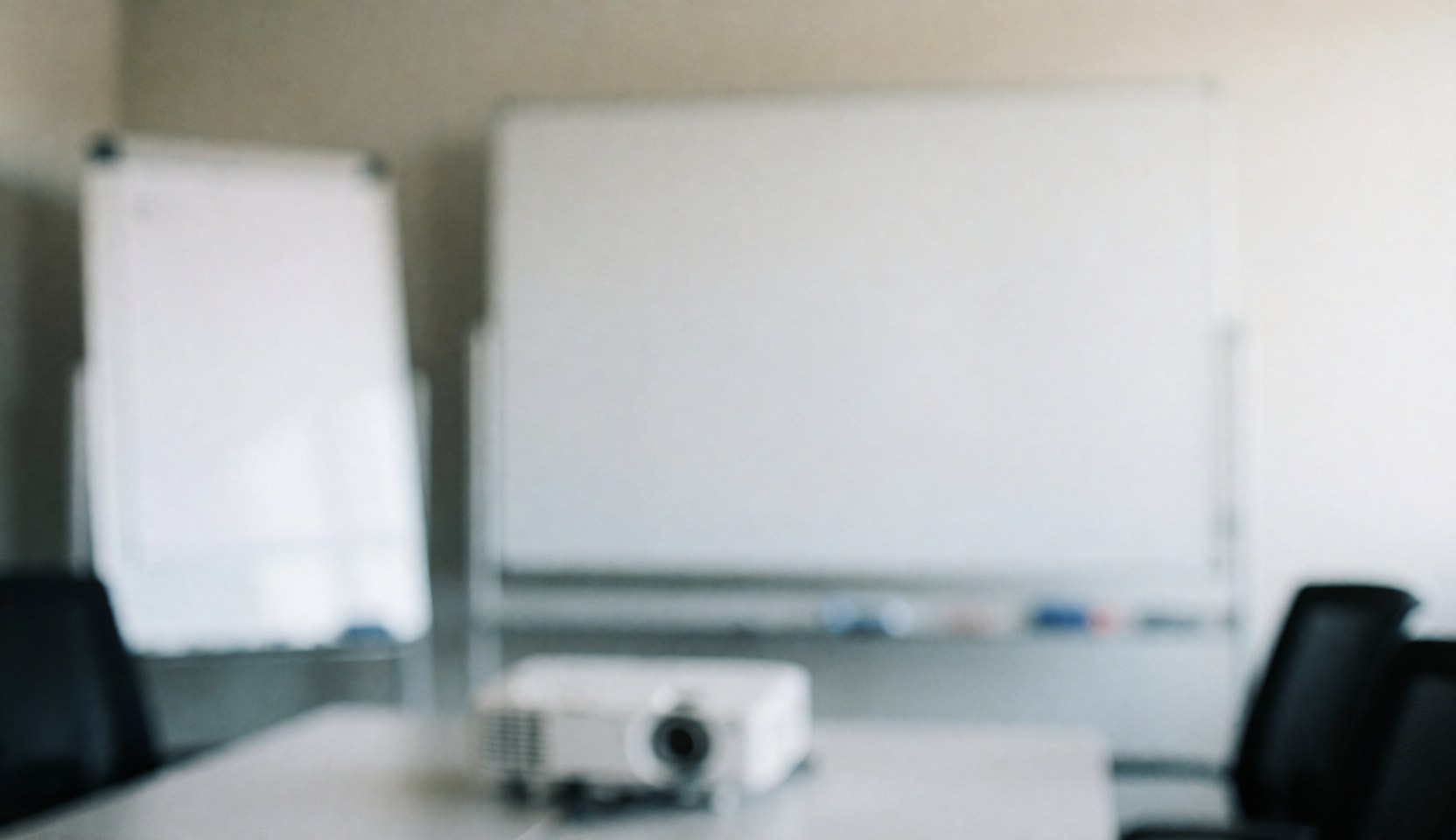 Vue d'une salle de réunion professionnelle équipée d'un grand tableau blanc, d'un projecteur et de chaises autour d'une table.