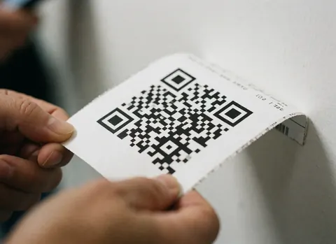 Mains tenant un billet de voyage avec code QR visible sur fond blanc pour une agence de voyages.