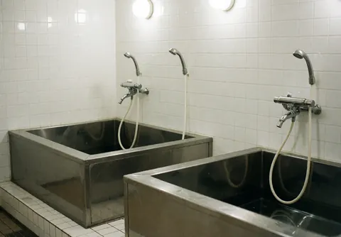 Baignoire professionnelle pour chiens avec tuyaux en acier inoxydable, murs carrelés blancs, propre et prête pour le lavage des animaux.