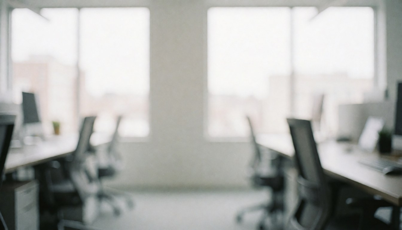 Un espace de travail moderne et aéré comprenant un bureau, une chaise et une grande fenêtre laissant entrer la lumière naturelle sur un fond blanc et gris flou.