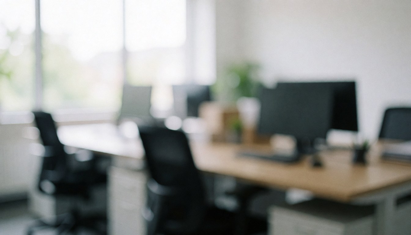 Arrière-plan flou d'un bureau moderne avec bureaux, chaises et ordinateurs, éclairage naturel par la fenêtre, ambiance professionnelle et calme.