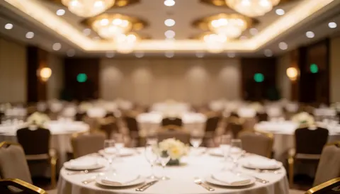 Vue d'un salon de banquet élégant avec des tables rondes couvertes de nappes blanches, des couverts, des verres et une lumière douce en arrière-plan flou pour texte ou publicité.