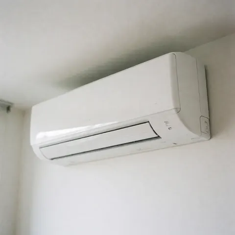 Vue d'une unité intérieure de climatiseur moderne montée sur un mur blanc dans une maison résidentielle, illustrant le confort thermique et l'efficacité énergétique.