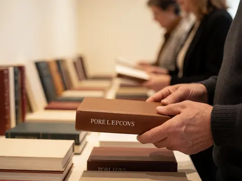 Des mains tenant un livre au titre en relief, avec d'autres livres flous en arrière-plan dans une librairie.