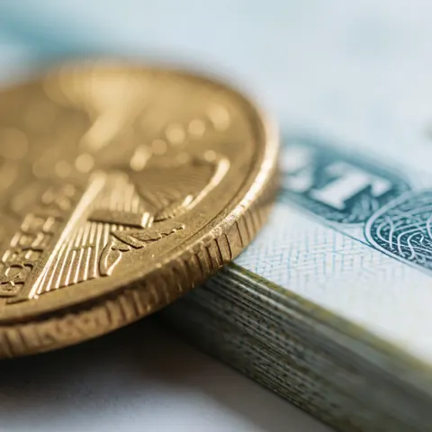 Vue macro d'une pièce de monnaie en or massif mettant en valeur son éclat métallique et ses reliefs gravés sur un fond clair.