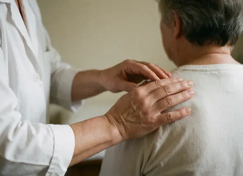 Mains du thérapeute effectuant un massage doux sur l'épaule du client pour favoriser la relaxation et le bien-être en spa.