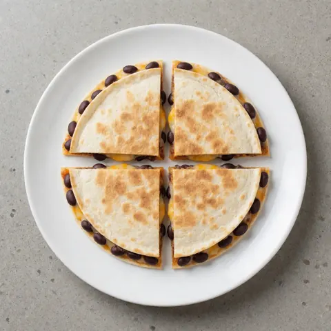 Une quesadilla aux haricots noirs et fromage fondu, présentée sur une assiette blanche posée sur une surface en béton, idéale pour la restauration rapide.