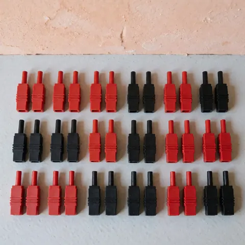 Vue de dessus montrant des connecteurs électriques disposés sur une surface grise avec un mur terracotta en arrière-plan sous éclairage naturel.