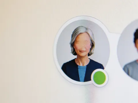 Gros plan d'un avatar utilisateur sur une interface numérique affichant un statut vert, posé sur un fond mural aux tons chauds.