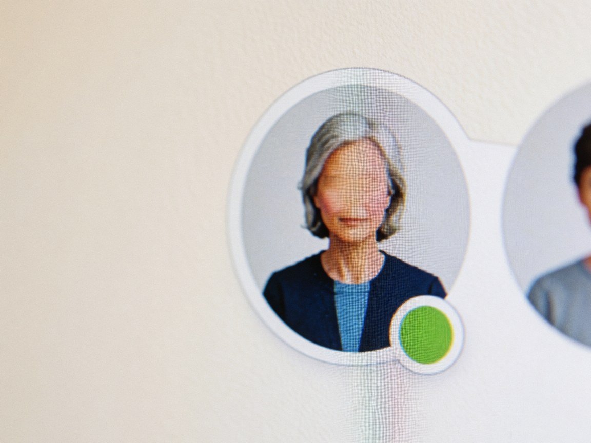Gros plan d'un avatar utilisateur sur une interface numérique affichant un statut vert, posé sur un fond mural aux tons chauds.