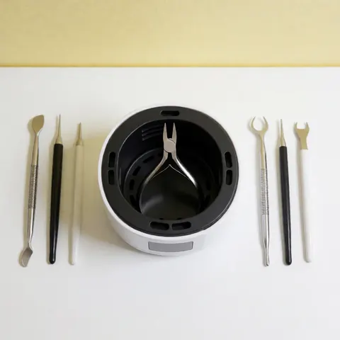Vue de dessus d'un kit d'outils professionnels de manucure disposés sur fond blanc et jaune, incluant pinces, brosses et instruments en métal pour l'hygiène des ongles.