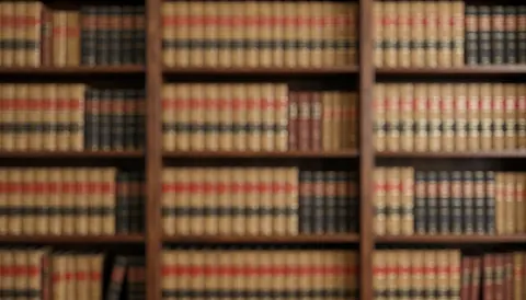 Étagères remplies de livres juridiques anciens créant un arrière-plan flou aux tons marron et beige, idéal pour superposer du texte dans un contexte professionnel.