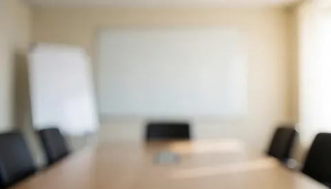 Vue d'une salle de réunion professionnelle vide comprenant une grande table de conférence et un tableau blanc sur le mur pour des présentations.