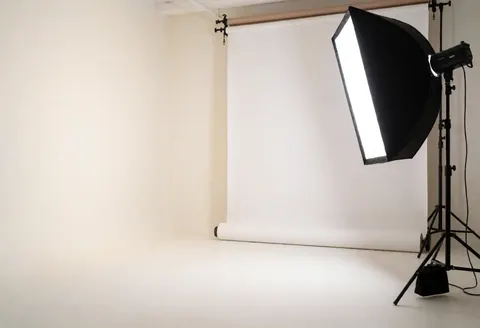 Intérieur d'un studio de photographie vide, éclairé par une lumière diffuse sur un fond blanc, idéal pour la prise de vue de produits commerciaux.