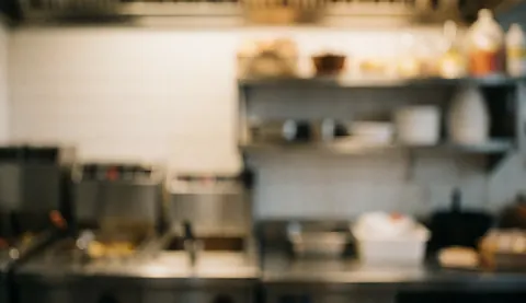 Arrière-plan de cuisine de restaurant avec friteuses et étagères floues, éclairage chaleureux, idéal pour ajouter du texte dans un contexte professionnel.