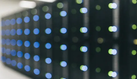 Arrière-plan de serveurs dans un datacenter avec des lumières bleues et vertes floues, idéal pour les textes sur le logiciel et les startups.