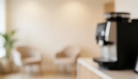 Arrière-plan flou d'un studio avec chaises et machine à café, idéal pour ajouter du texte sur une surface neutre et chaleureuse.