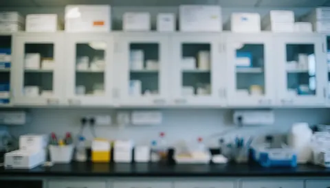 Arrière-plan flou d'un laboratoire comportant des étagères blanches, des boîtes et du matériel scientifique, idéal pour intégrer des textes ou des présentations professionnelles.