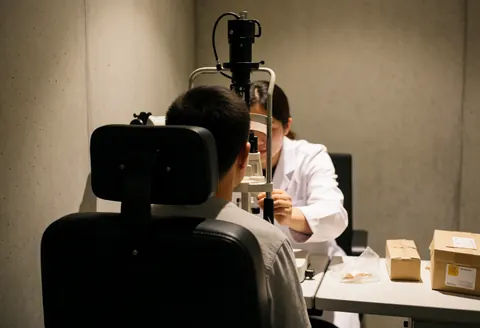 Un optométriste effectue un examen de la vue sur un patient assis dans une salle de consultation.