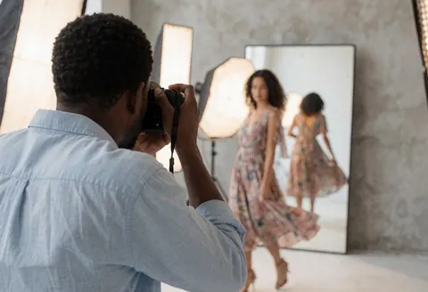 Un modèle pose dans un studio lumineux avec des miroirs et des éclairages professionnels pour une séance photo de mode.