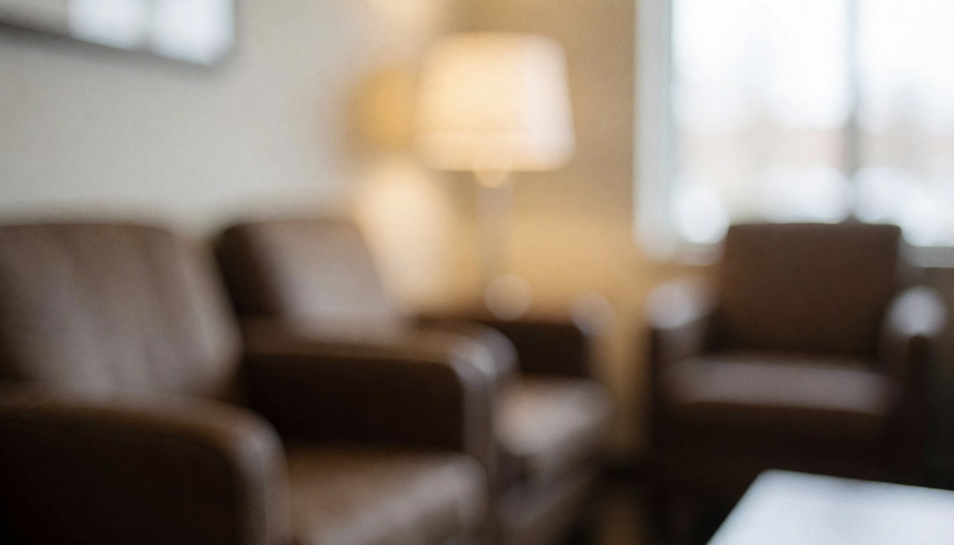 Intérieur d'une salle d'attente apaisante avec des fauteuils confortables, une lampe et une lumière tamisée sur un fond flou aux tons chauds.