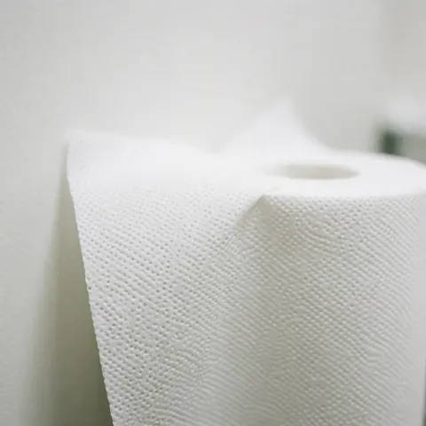 Gros plan sur un rouleau de papier blanc, montrant la texture du matériau et le bord découpé, évoquant l'hygiène et la propreté dans un contexte professionnel ou médical.