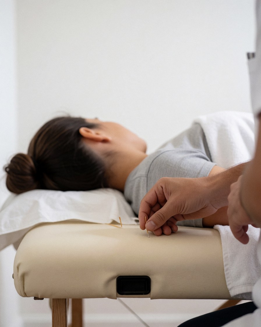 Un patient allongé sur une table de traitement, les yeux fermés, dans un état de relaxation profonde après une séance d'acupunctures.