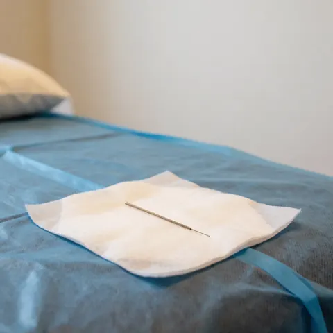Bouteille d'eau destinée à l'acupuncture posée sur une table de traitement, accompagnée d'un tissu stérile dans un environnement propre et professionnel.