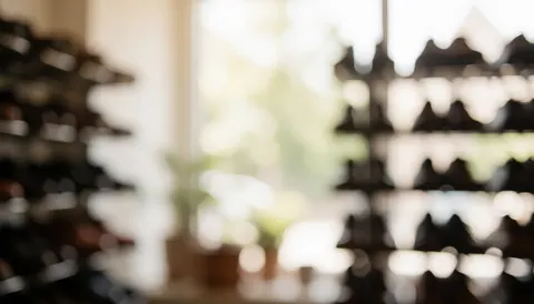 Fond neutre et flou de chaussures suspendues sur des cintres, évoquant un espace de séchage naturel et professionnel pour le secteur du commerce de détail.