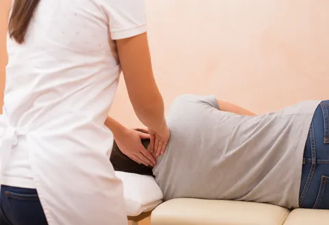 Un thérapeute effectue un massage cervical professionnel sur un client allongé sur une table de massage dans un cabinet.