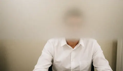 Homme en chemise blanche assis dans un bureau avec un fond flou, idéal pour des textes commerciaux et des accords.