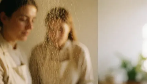 Des cheveux tombent dans un studio de coiffure aux tons chauds, avec un fond doux et un espace libre à droite pour le texte.