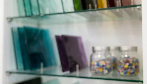 Arrière-plan de verrerie décorative avec étagères en verre coloré et bocaux en verre en flou, idéal pour les textes commerciaux.