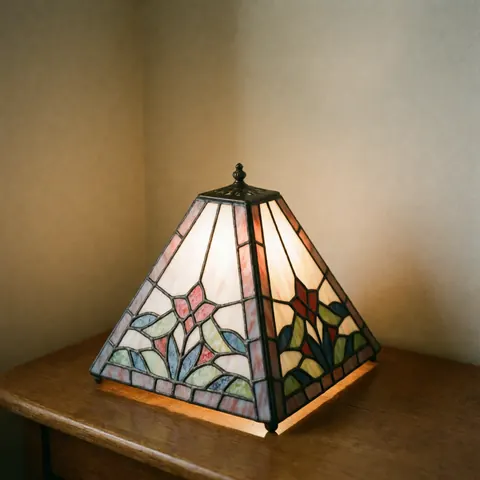 Lampe en cristal décoratif à patine métallique posée sur une table en bois devant un mur beige, éclairage chaleureux pour intérieur.