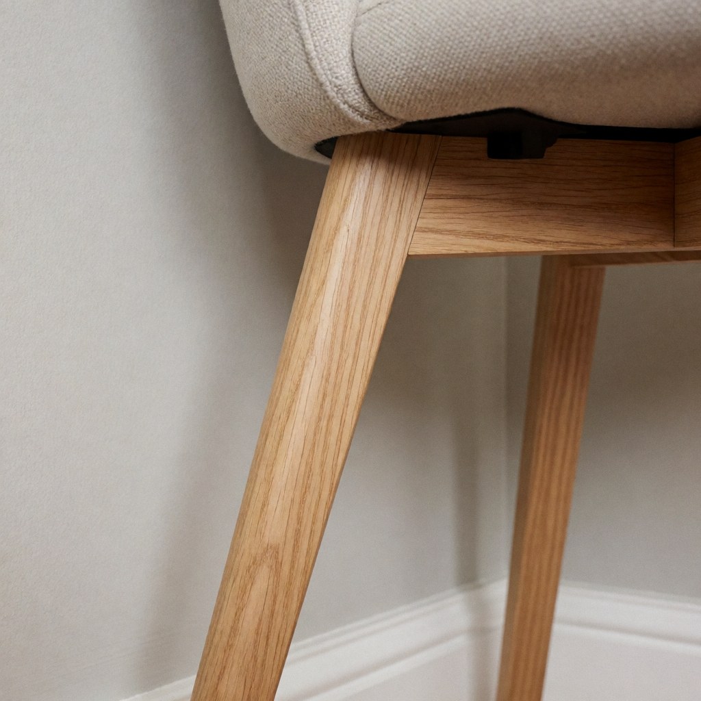 Gros plan montrant la jonction d'une chaise en bois clair lors d'une réparation, avec visible le grain du bois et un cheville de fixation.