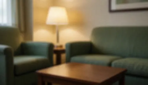 Salle d'attente avec canapés verts, table basse en bois et lampe, ambiance chaleureuse et relaxante, idéale pour textes sur le bien-être et le reiki.