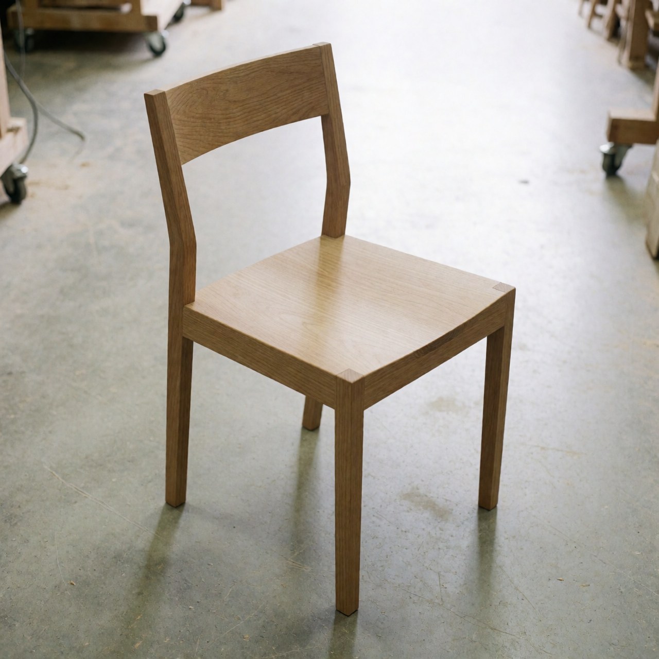 Vue de face d'une chaise style Shaker en bois massif restaurée, montrant les détails du travail de menuiserie et la finition naturelle sur fond neutre.