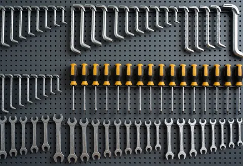 Mur d'outils organisé pour la réparation de vélos avec clés, tournevis et douilles dans un atelier professionnel et propre.