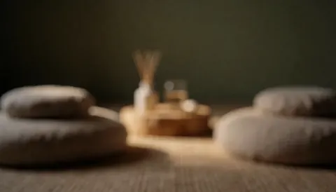 Un espace intérieur apaisant servant de fond, orné de coussins doux, d'un diffuseur d'huiles essentielles et baigné d'une lumière tamisée créant une atmosphère de calme.