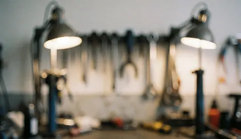Arrière-plan d'atelier de mécanique avec outils suspendus sur un mur gris et un fond flou pour texte