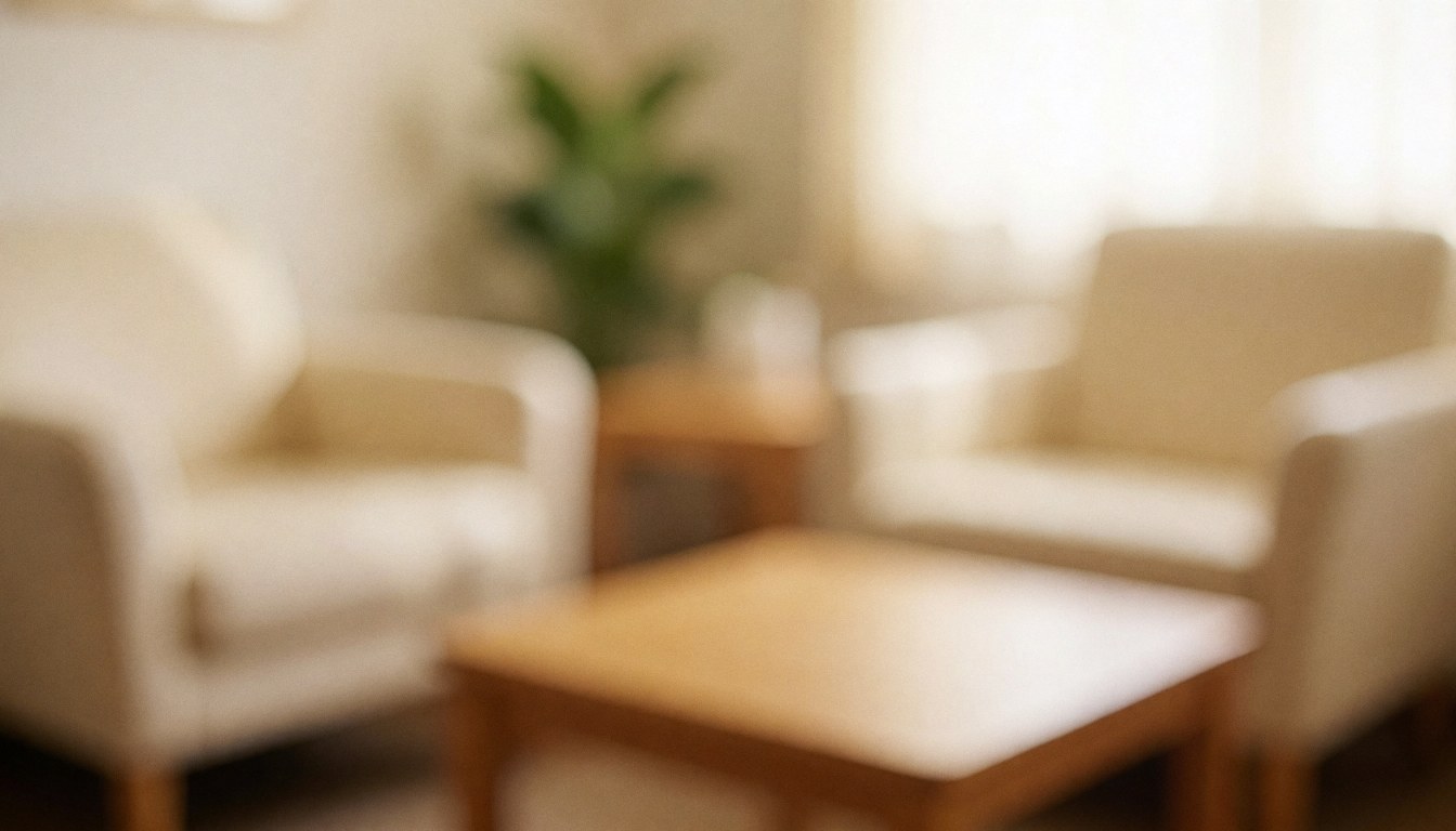 Intérieur d'une salle d'attente d'ostéopathie avec canapés beige, table en bois et plante verte, éclairage chaleureux pour un fond neutre.
