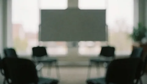 Salle de formation floue avec chaises disposées en cercle et tableau blanc, créant une atmosphère calme et professionnelle adaptée aux thérapies holistiques.