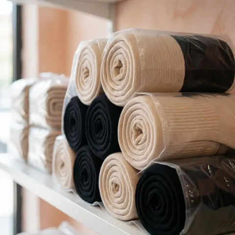 Des chaussettes de compression présentées dans des emballages transparents disposés sur une étagère, avec un éclairage naturel et un fond aux tons terracotta.