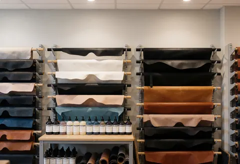 Entrepôt de cuir avec des rouleaux de différentes couleurs et des bouteilles de teintures, idéal pour la maroquinerie et le travail du cuir, ambiance professionnelle et ordonnée.