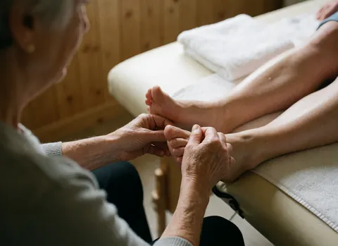 Gros plan sur les pieds d'une femme enceinte recevant un massage relaxant avec des mains expertes, mettant en valeur le soin et le bien-être.