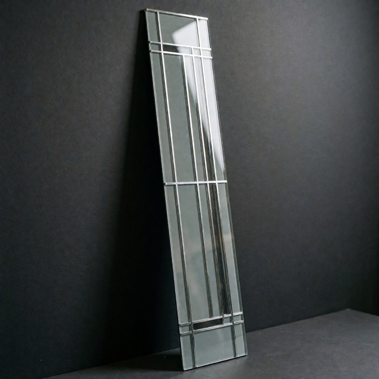 Panneau mural décoratif aux lignes géométriques noires, en verre et métal, éclairé en studio pour un usage produit.