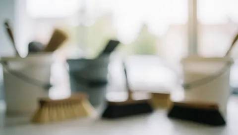 Vue floue d'une station de nettoyage équipée de brosses et de seaux, éclairage doux et ambiance sereine, idéale pour ajouter du texte sur un site professionnel.