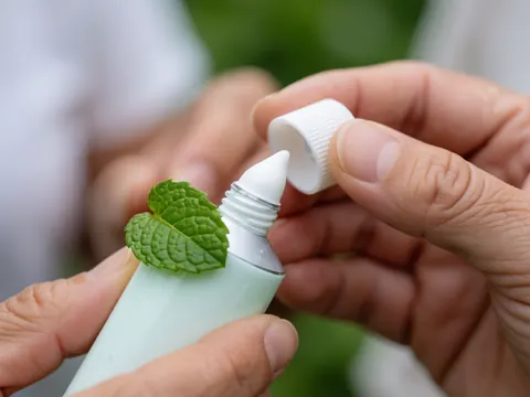 Gros plan montrant la texture onctueuse d'une crème à la menthe verte accompagnée d'une feuille fraîche posée dessus, évoquant le bien-être et les soins naturels.
